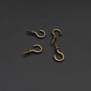 Puede incluir: Cuatro ganchos de tornillo de oro antiguo con un diseño simple y curvo.