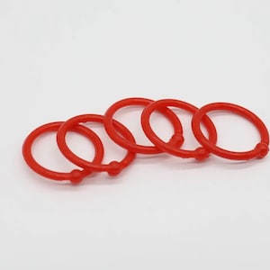 May include: Five red plastic rings, likely used for binding papers or organizing items.