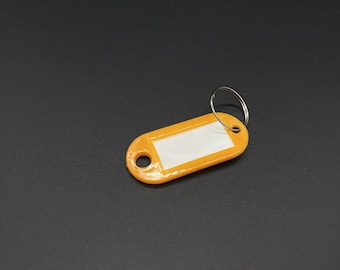 May include: Orange plastic key tag with a clear rectangular label and a silver metal ring.