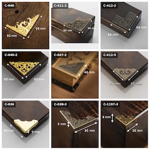 Può includere: Una collezione di nove paraspigoli in metallo per scatole e libri, con varie finiture in oro, bronzo e ottone con motivi complessi. Ogni pezzo è etichettato con un codice e include misure visibili in millimetri.