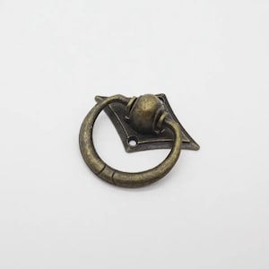 May include: Antique bronze ring pull cabinet handle with a diamond-shaped base.