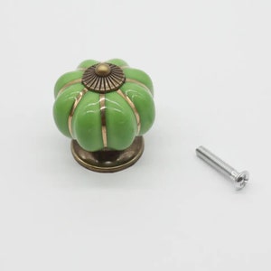 May include: Green ceramic cabinet knob with gold accents and a screw. The knob is shaped like a pumpkin.