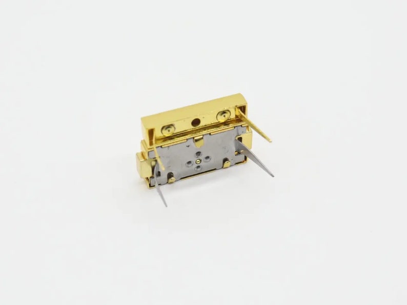May include: A gold-colored electronic component with four metal pins. The component has a rectangular shape and a silver-colored base.