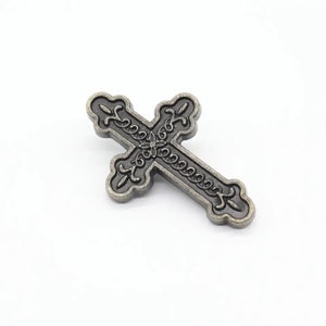 May include: A silver-toned metal cross with an ornate design. The cross has a black finish and intricate details.