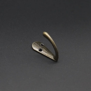May include: A single antique gold-toned metal hook with two screw holes. The hook is curved and has a decorative design.