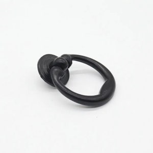 May include: Black ring pull cabinet door handle with a round base.