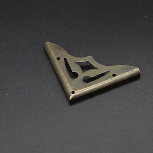 May include: A brass corner bracket with a decorative design. The bracket is a light gold colour and has a smooth finish.