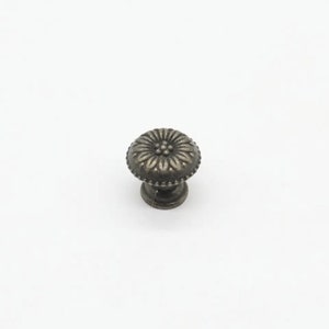 May include: A silver-toned metal cabinet knob with a floral design. The knob has a round base and a raised, detailed flower pattern.