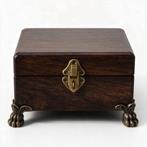 May include: A rectangular dark brown wooden box with a smooth finish, featuring a brass-toned metal latch on the front and four decorative metal feet shaped like animal paws at the base, providing a stable foundation for the storage container.