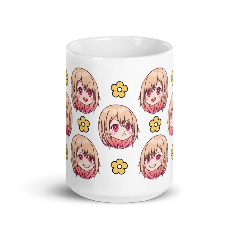 May include: White ceramic mug featuring a repeating pattern of a cartoon anime girl with blonde hair and pink cheeks. The girl has different facial expressions. The background is white with yellow flower accents.