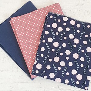 May include: Three fabric swatches in navy blue, dusty rose with white polka dots, and navy blue with a floral pattern. The floral pattern features pink roses and white leaves. Suitable for sewing and craft projects.