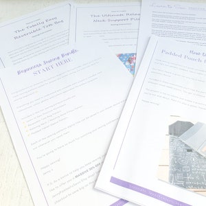 May include: A white sheet of paper with the title "Beginners Sewing Bundle" and a list of sewing projects included in the bundle. The projects include a reversible tote bag, a neck support pillow, and a padded pouch. The paper is on a white surface with sewing supplies.