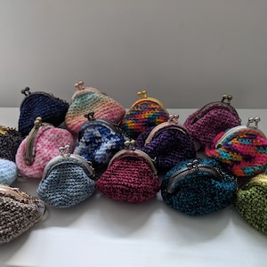Puede incluir: Una colección de 15 monederos de ganchillo en varios colores y patrones, incluyendo rosa, azul, verde, rojo y marrón. Los monederos son todos pequeños y tienen un cierre de metal.