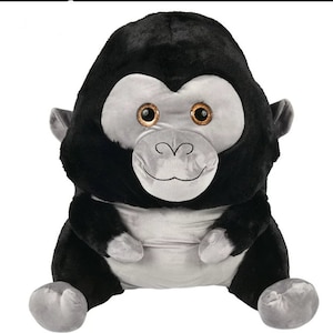以下が含まれることがあります： グレーの顔と大きな茶色の目をした黒いゴリラのぬいぐるみ。ゴリラは足を組んで座っており、友好的な表情をしています。