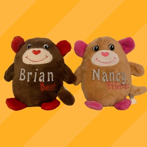 May include: Two plush brown and tan monkey toys with embroidered faces and pink and red ears. The brown monkey has the name "Brian Best" embroidered on its chest. The tan monkey has the name "Nancy Friends" embroidered on its chest.