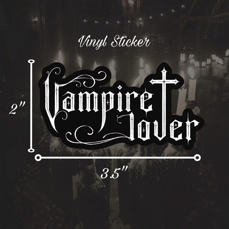 May include: Black vinyl sticker, 3.5 inches wide and 2 inches tall, with the words "Vampire Lover" in a gothic font. The sticker has a cross design and decorative swirls. The text "Vinyl Sticker" is above the main text.