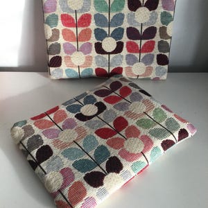 May include: Two zippered pouches with a floral pattern in shades of red, pink, green, blue, and brown. The pouches are made of a woven fabric with a textured surface.