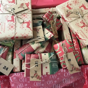May include: A collection of wrapped Christmas gifts in a box. The gifts are wrapped in festive paper with reindeer, snowflakes, and Christmas tree patterns. Each gift is tied with twine and has a small tag. The color scheme includes red, green, and cream.