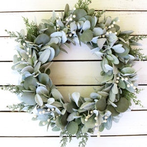 May include: A green and white eucalyptus wreath with white berries. The wreath is made of artificial greenery and is perfect for a farmhouse or rustic decor style.