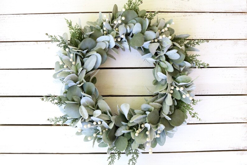 May include: A green and white eucalyptus wreath with white berries. The wreath is made of artificial greenery and is perfect for a farmhouse or rustic decor style.