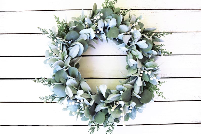 May include: A silver-green eucalyptus wreath with white berries, perfect for a farmhouse or rustic decor theme.