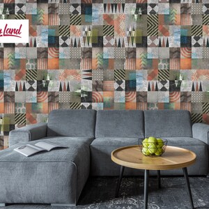 Peut inclure: Un canapé d'angle gris avec une méridienne est placé devant un mur recouvert d'un papier peint patchwork coloré. Le papier peint présente une variété de motifs géométriques et de couleurs, notamment le rouge, l'orange, le jaune, le vert, le bleu et le gris. Une table basse en bois avec un bol de pommes vertes se trouve devant le canapé.