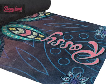 May include: A blue yoga mat with a colorful patterned design and the word "Bossy" written in pink. The mat is rolled up and the end is visible.