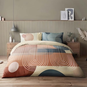Può includere: Un copripiumino con un motivo geometrico in tonalità arancio, marrone, beige e blu. Il motivo presenta linee curve e cerchi.