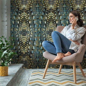 May include: A woman sits in a chair with a crocodile skin patterned wallpaper behind her. She is talking on a cell phone and has her feet up on the chair. The chair is light brown and has a light brown rug with a chevron pattern in front of it.