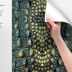 May include: A close-up of a crocodile skin wallpaper with a green, blue, and yellow color scheme. The wallpaper is being applied to a white wall.