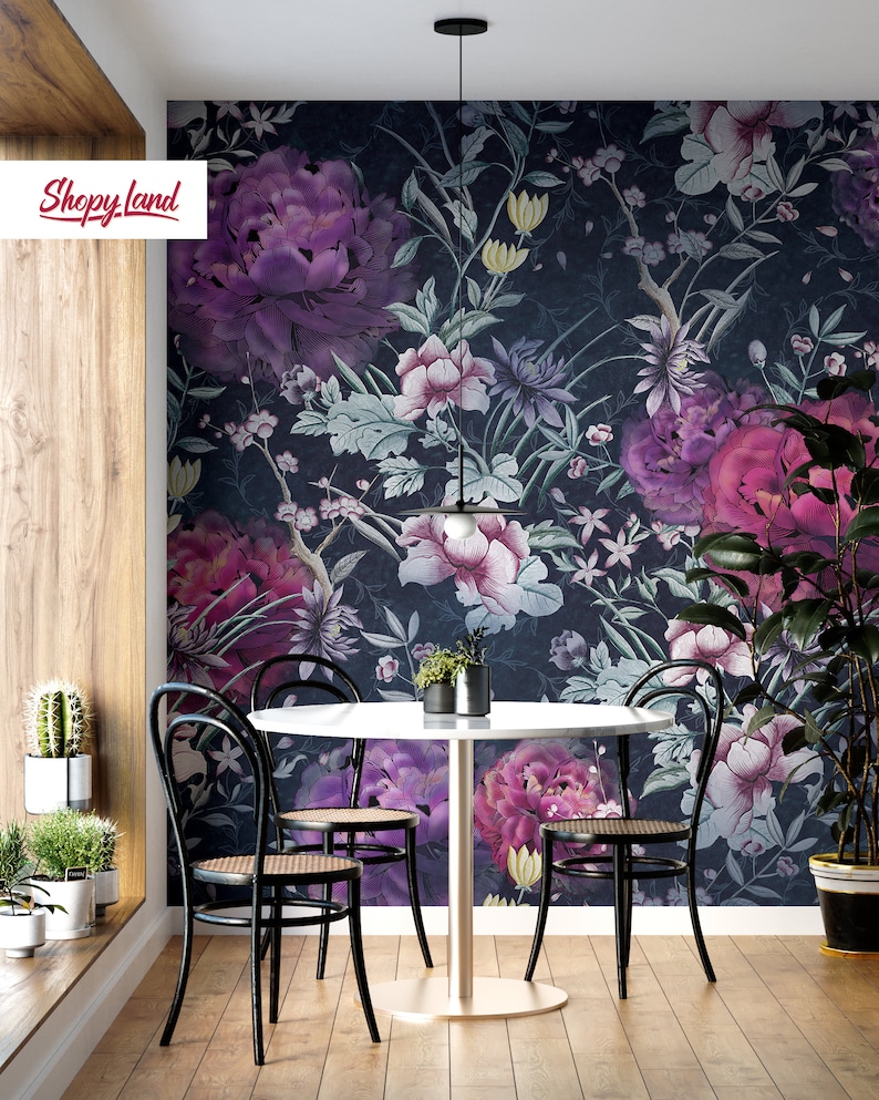 May include: A dining room with a round white table and four black chairs. The wall is covered in a dark floral wallpaper with purple, pink, and white flowers. A black pendant light hangs above the table.