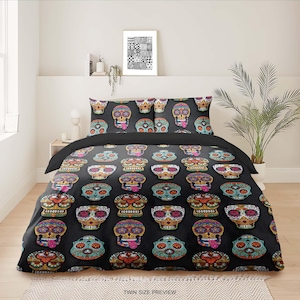 May include: Twin size bedding set featuring a black background with a repeating pattern of colorful sugar skulls. The skulls have intricate designs in various colors, including orange, blue, and green. The set includes a comforter and two pillowcases.