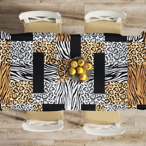 Puede incluir: Un mantel de mesa con un diseño de patchwork de estampados de animales, incluyendo leopardo, cebra y rayas de tigre. El mantel es en tonos de marrón, negro y blanco.