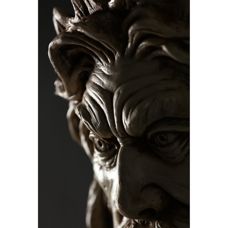 May include: Close-up of a detailed, sculpted face with a furrowed brow and intense eyes. The face is made of a light brown material and appears to be part of a larger sculpture.
