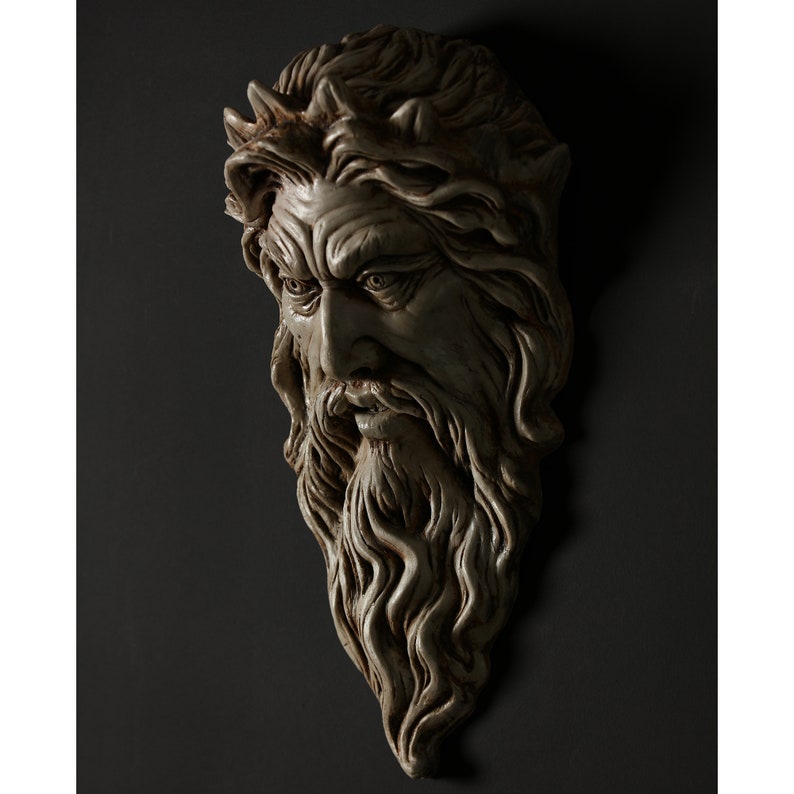 May include: A detailed, white plaster sculpture of a man's face with a long beard and a crown of thorns. The sculpture is mounted on a dark gray wall.