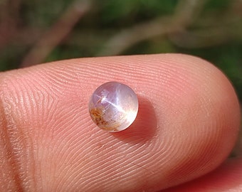 May include: A round, clear, light purple gemstone with a star-shaped reflection in the center. The gemstone is set in a silver ring.