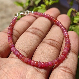 Peut inclure: Un bracelet délicat composé de petites perles rondes de pierres précieuses roses et rouges. Le bracelet a un fermoir argenté.