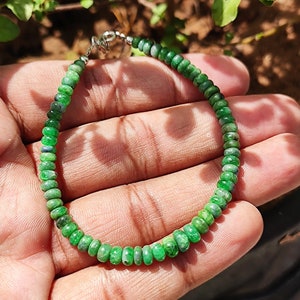 May include: A green gemstone bracelet with a silver clasp. The bracelet is made of small, round beads.