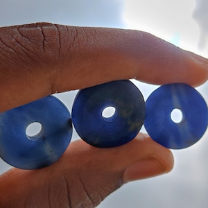 Peut inclure: Trois perles bleues en forme de beigne avec un trou au centre. Les perles sont empilées les unes sur les autres.