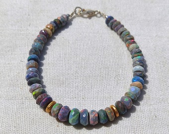 May include: A silver and gold bracelet with a clasp closure. The bracelet is made of small, iridescent opal beads.