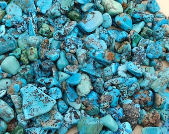 Può includere: Una collezione di pietre turchesi di varie forme e dimensioni. Le pietre sono di un colore blu-verde vibrante con segni neri e marroni.