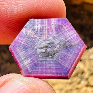 Peut inclure: Une pierre précieuse hexagonale violette et rose avec un motif en forme d'étoile au centre.