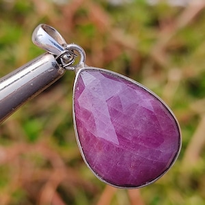 May include: A teardrop-shaped pendant with a faceted pink gemstone set in sterling silver.