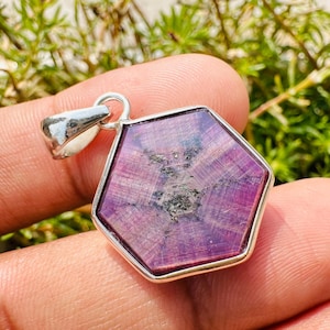 May include: A hexagonal pendant featuring a purple gemstone set in sterling silver. The gemstone displays a star-like pattern and a deep purple colour.