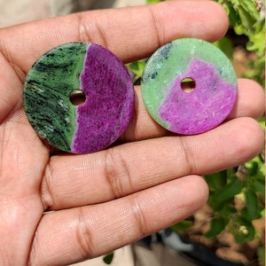 Può includere: Due perline rotonde di pietra preziosa verde e viola con un foro al centro. Le perline hanno un diametro di circa 2,5 cm.