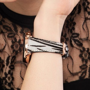 May include: A black and white zebra print watch band with a rose gold watch face.
