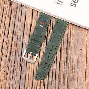 May include: Two green leather watch straps with white stitching. One strap has red, white, and blue stitching detail.