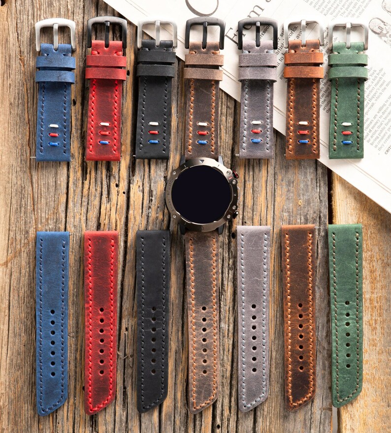 May include: A set of 10 leather watch bands in various colors, including blue, red, black, brown, gray, and green. The bands are all made of leather and have a stitched design. The bands are shown on a wooden surface.