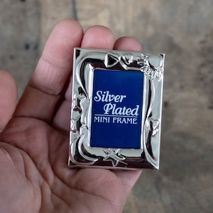 Peut inclure: Un mini cadre en argent plaqué avec un fond bleu et le texte "Silver Plated Mini Frame".