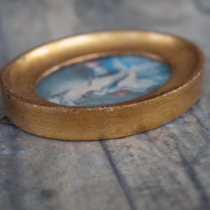 A lower-angle perspective showing the thickness and texture of the miniature oval frame resting on a surface.